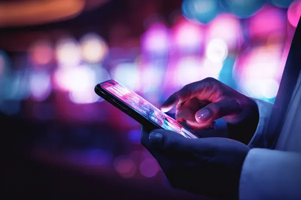 A woman smiling by bright slot machines showing lucky symbols, showcasing the exciting slot offerings at JILIX.